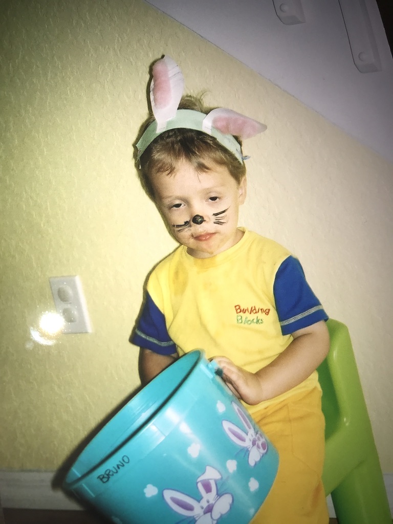 Bruno as a young child wearing bunny ears, holding an Easter basket with his name on it.
