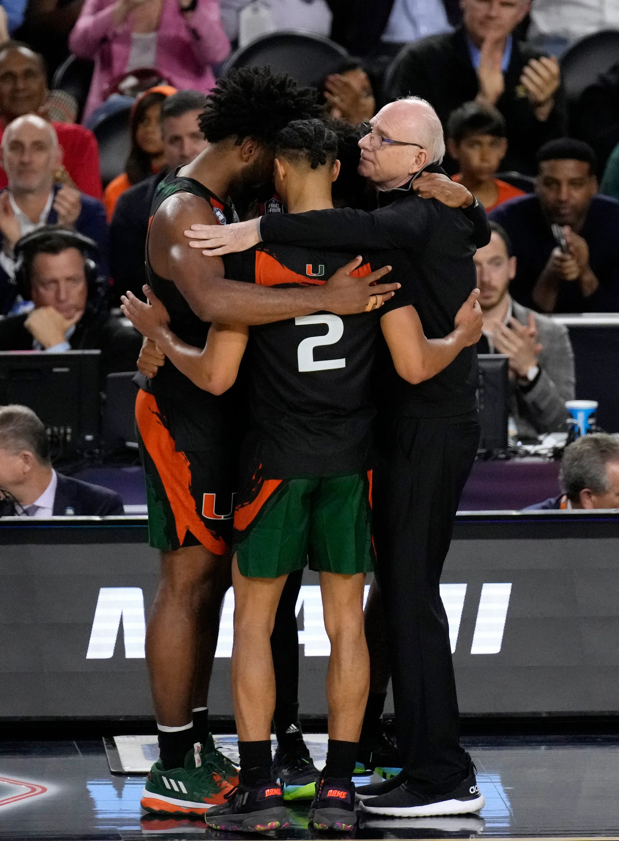 Miami Hurricanes players and head coach Jim Larrañaga embracing on the court during the 2023 Final Four run.