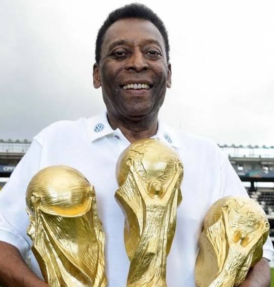 Pelé shaking hands with Muhammad Ali on the field before a match.