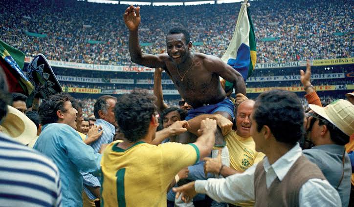 Pelé celebrating with a teammate after Brazil's 1970 World Cup win, fist raised in the air.